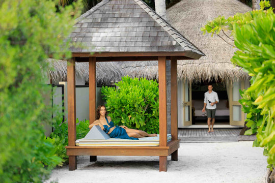 Angsana Velavaru, Dhaalu Atoll — guests at the thatched sala outside a Deluxe Beachfront Pool Villa