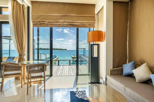 Angsana Velavaru, Dhaalu Atoll — living area of a Deluxe InOcean Pool Villa, with a table and chairs by the doors
