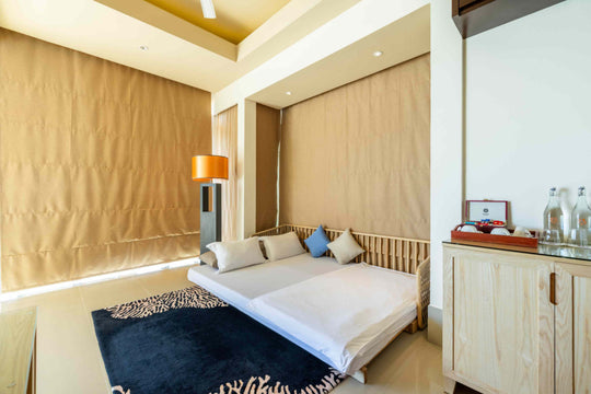 Angsana Velavaru, Dhaalu Atoll — the sofa bed in a Deluxe InOcean Pool Villa, made up beside a reading lamp