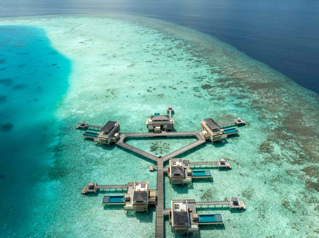 Angsana Velavaru, Dhaalu Atoll — aerial view of the InOcean cluster on the edge of the reef, with deep water beyond