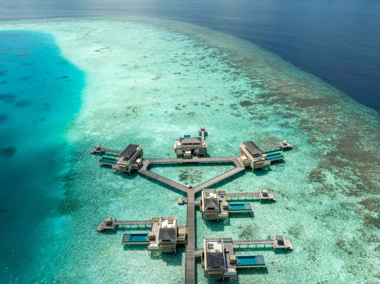 Angsana Velavaru, Dhaalu Atoll — aerial view of the InOcean cluster on the edge of the reef, with deep water beyond