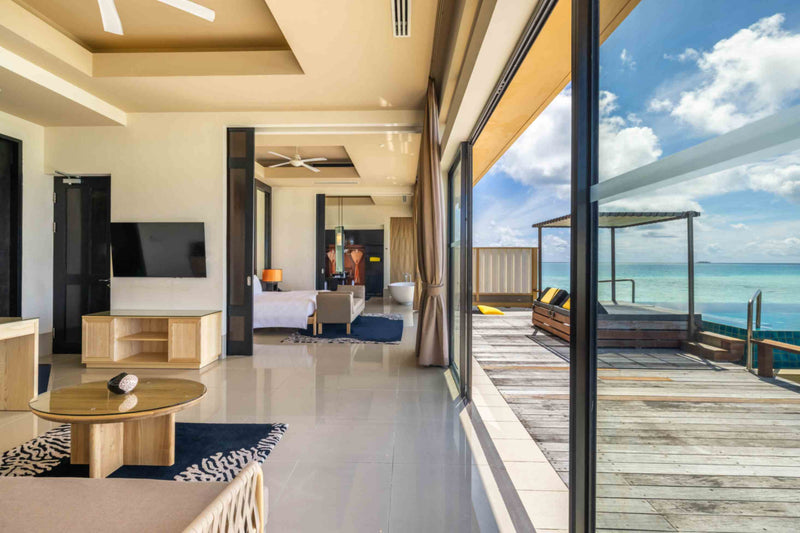 The living area of the two-bedroom overwater villa at Angsana Velavaru looking through to the bedroom and the deck.