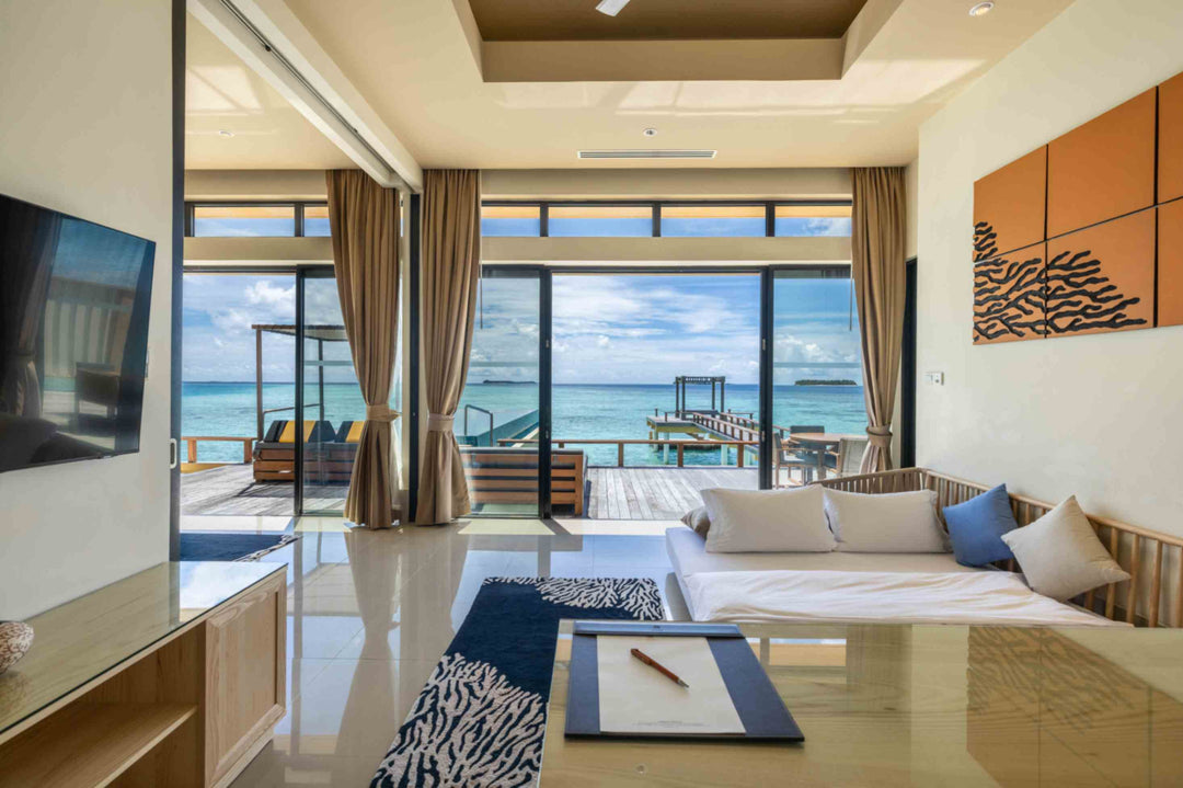 Angsana Velavaru, Dhaalu Atoll — sofa bed and television in the two-bedroom overwater villa, with the doors open to the deck