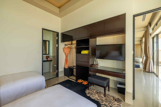 Angsana Velavaru, Dhaalu Atoll — the twin bedroom of the overwater villa, with wardrobe, television and dressing bench