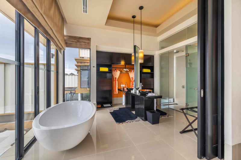 A Deluxe InOcean villa bathroom at Angsana Velavaru with a freestanding bath, wardrobe and walk-in shower.