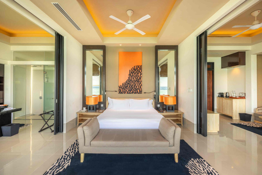 Angsana Velavaru, Dhaalu Atoll — InOcean Pool Villa bedroom with orange coral artwork and a bench at the foot of the bed