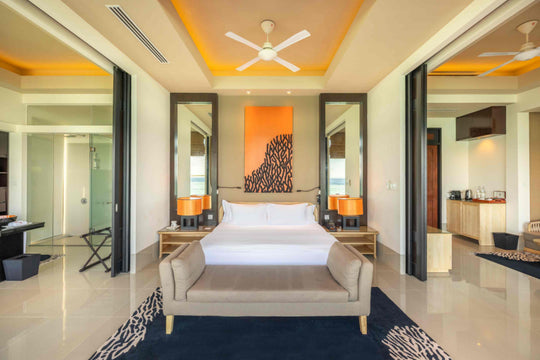Angsana Velavaru, Dhaalu Atoll — InOcean Pool Villa bedroom with orange coral artwork and a bench at the foot of the bed