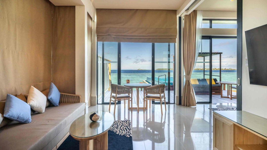 Angsana Velavaru, Dhaalu Atoll — the living area of an InOcean Pool Villa, with a banquette and doors onto the lagoon deck