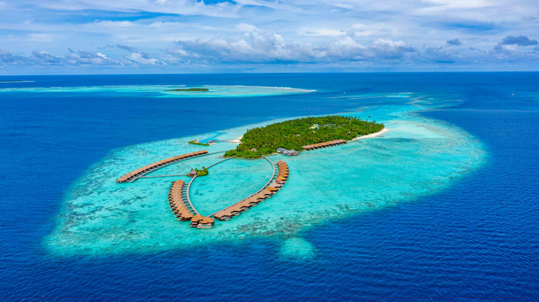 Ayada Maldives from a distance, the island and its overwater villas set in pale turquoise shallows