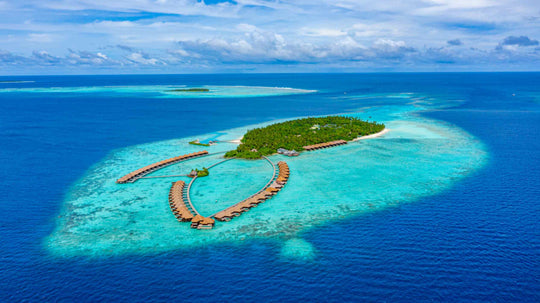 Ayada Maldives from a distance, the island and its overwater villas set in pale turquoise shallows