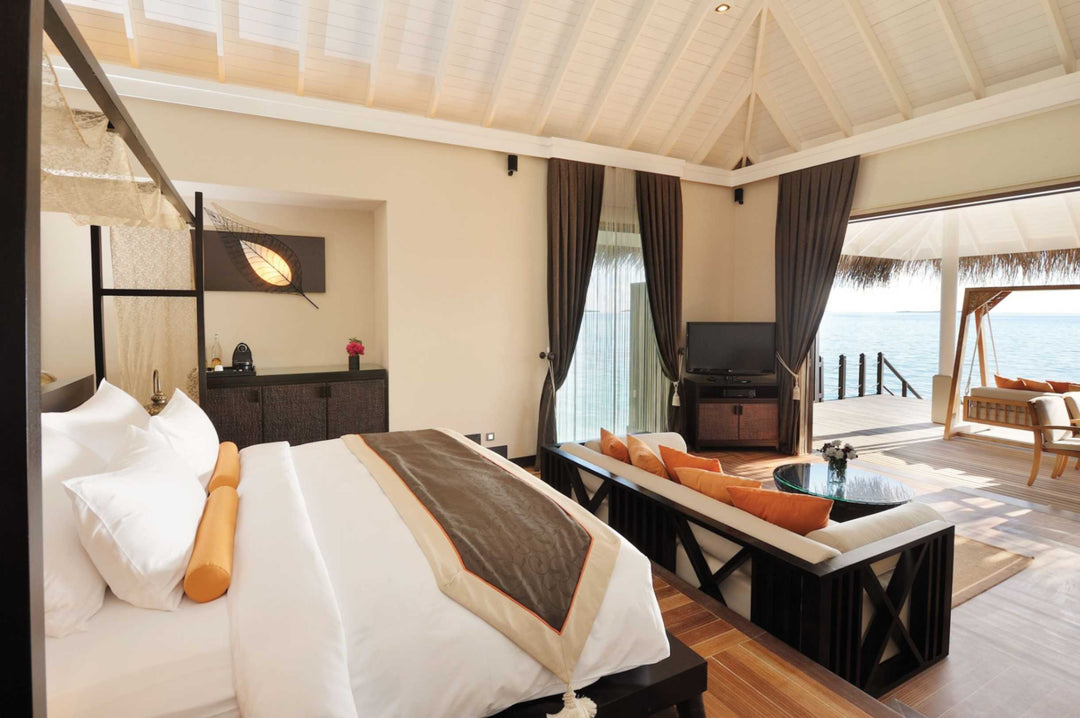 A lagoon suite bedroom at Ayada Maldives with a writing desk and doors to the deck