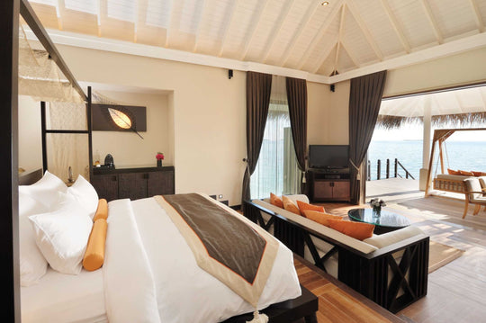 A lagoon suite bedroom at Ayada Maldives with a writing desk and doors to the deck