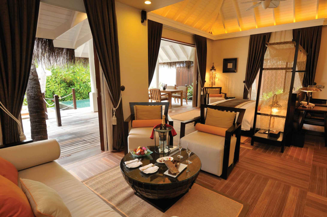 A beach villa living area at Ayada Maldives, round table laid for two beside the bed