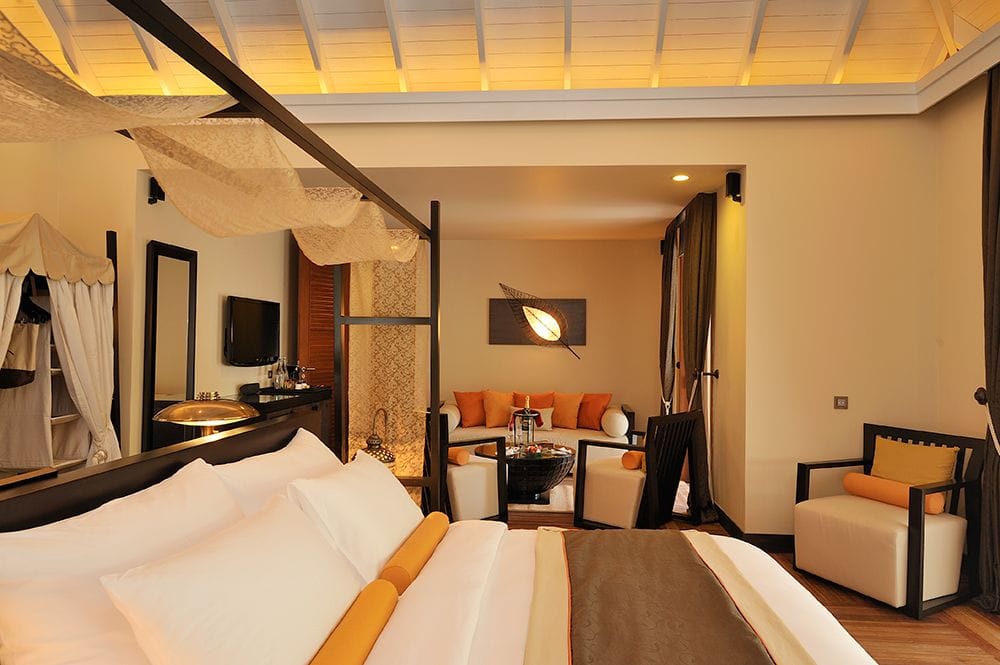 A villa living space at Ayada Maldives with orange cushions and doors open to the garden