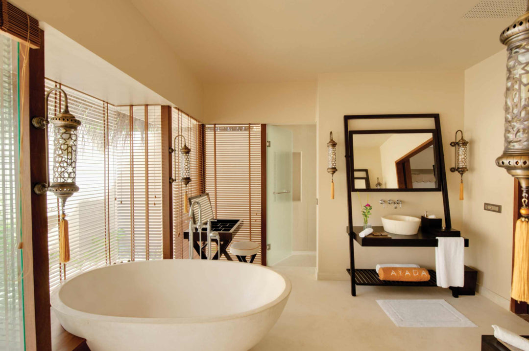 A villa bathroom at Ayada Maldives, oval tub and mirrored vanity under a white ceiling