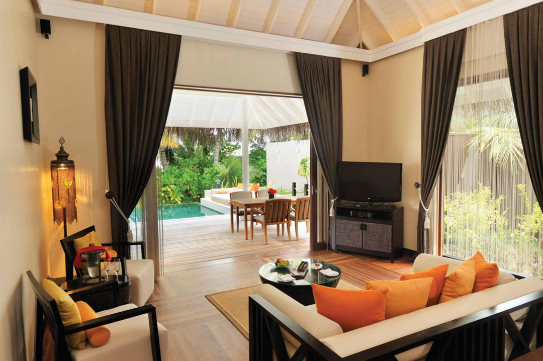A sunset beach suite living room at Ayada Maldives with an orange sofa facing the deck