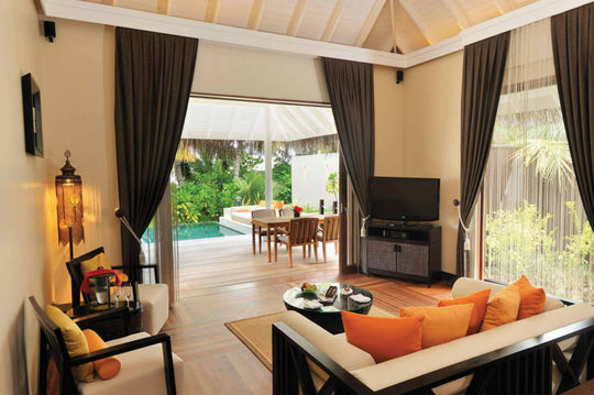 A sunset beach suite living room at Ayada Maldives with an orange sofa facing the deck