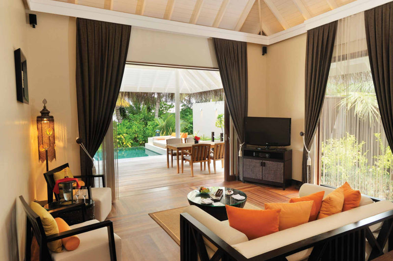 A sunset beach suite living room at Ayada Maldives with an orange sofa facing the deck