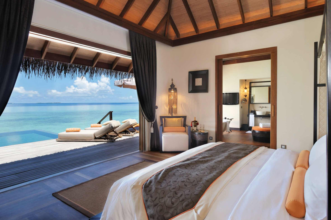 A sunset ocean suite bedroom at Ayada Maldives opening onto the deck and its pool