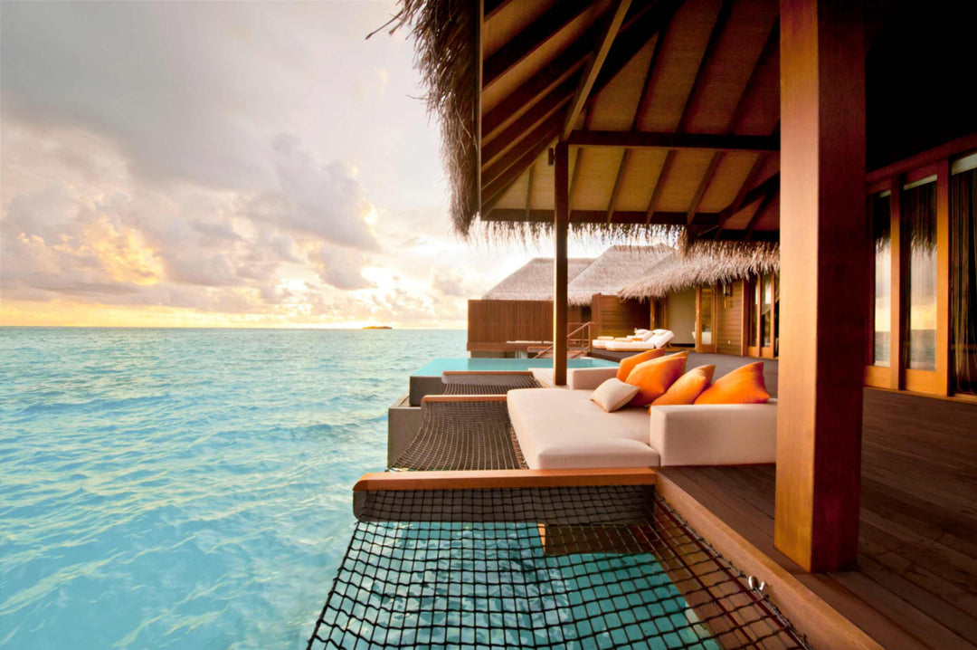 A sunset ocean suite deck at Ayada Maldives late in the day, daybed beside the tiled pool