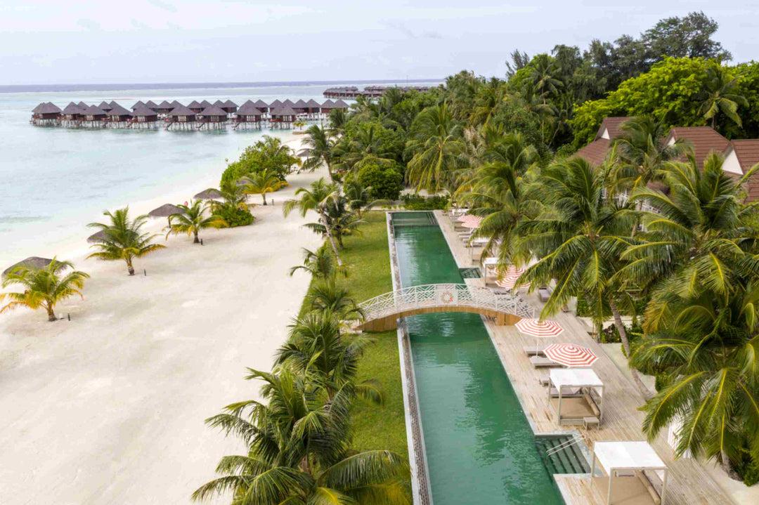 Sun Siyam Olhuveli, South Malé Atoll — aerial view of the long green pool running beside the beach, overwater villas beyond
