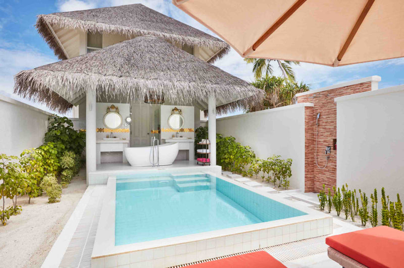 An open-air bathroom at Sun Siyam Iru Veli under two thatched roofs, twin basins and a freestanding tub beside the private pool.