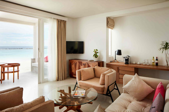 Sun Siyam Iru Veli, Dhaalu Atoll — sitting room with armchairs, a glass coffee table and doors open to the beach