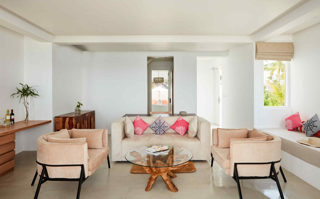 Sun Siyam Iru Veli, Dhaalu Atoll — living room with two facing sofas and a glass table on a tree-trunk base