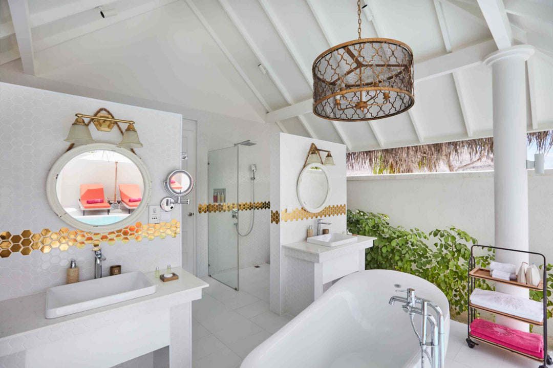 Sun Siyam Iru Veli, Dhaalu Atoll — bathroom with a drum chandelier, twin round mirrors, glass shower and a freestanding tub open to the garden