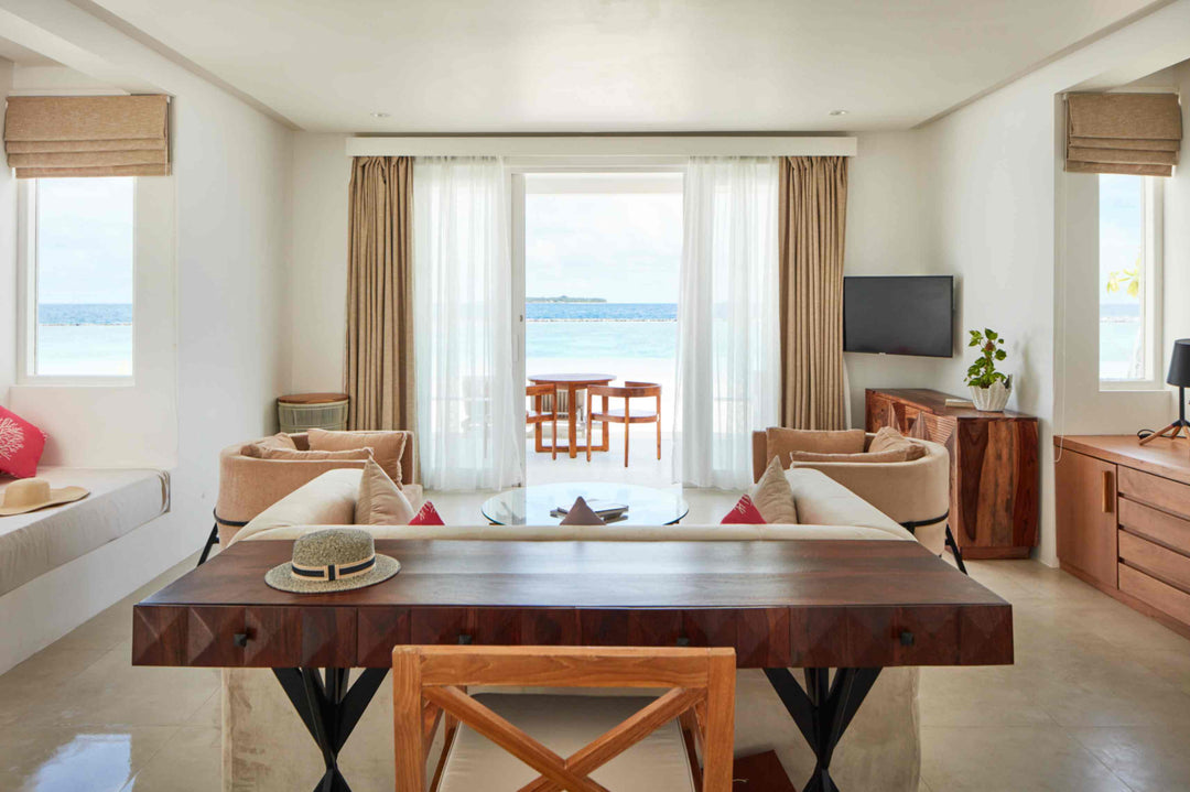 Sun Siyam Iru Veli, Dhaalu Atoll — dining and living room with a long timber table and doors open to the sea