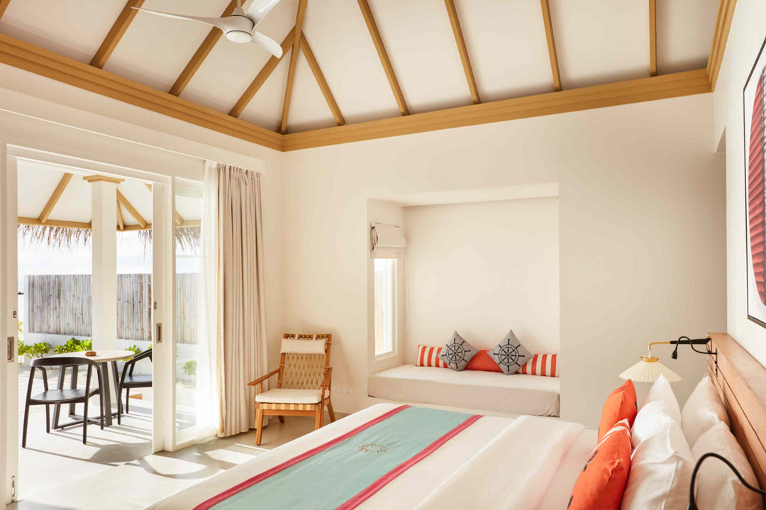 Sun Siyam Iru Veli, Dhaalu Atoll — bedroom under a vaulted ceiling with a window seat and doors to a terrace