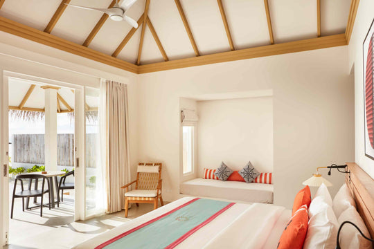 Sun Siyam Iru Veli, Dhaalu Atoll — bedroom under a vaulted ceiling with a window seat and doors to a terrace