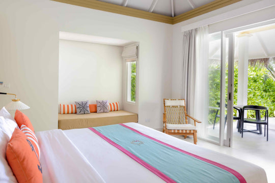 Sun Siyam Iru Veli, Dhaalu Atoll — bedroom with a cushioned bench under the window and doors to a garden terrace