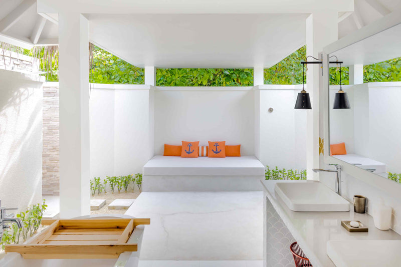 An open-air bathroom court at Sun Siyam Iru Veli with a daybed and planting along the walls.