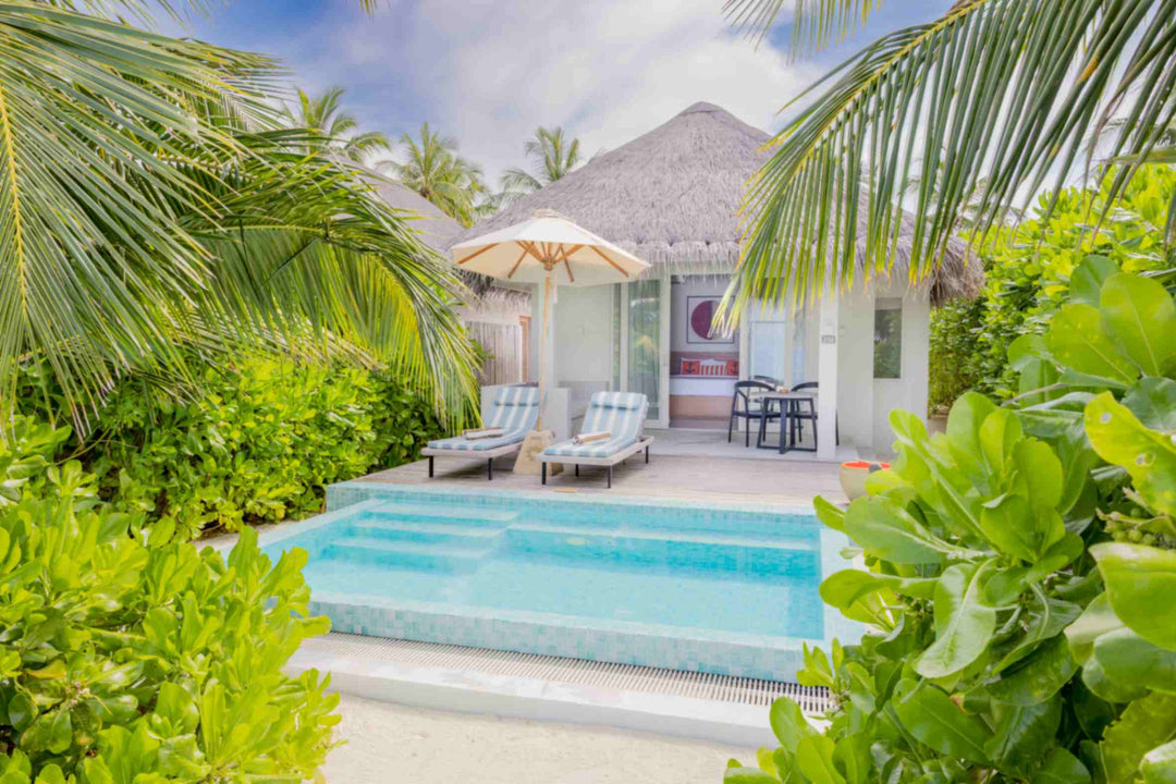 Sun Siyam Iru Veli, Dhaalu Atoll — beach villa seen through the palms, its private pool and loungers under a parasol