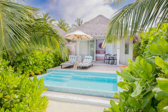 Sun Siyam Iru Veli, Dhaalu Atoll — beach villa seen through the palms, its private pool and loungers under a parasol