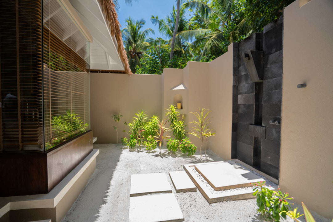 The open air shower at a beach villa at Ayada Maldives, walled in white with planting around it