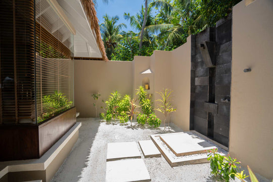 The open air shower at a beach villa at Ayada Maldives, walled in white with planting around it