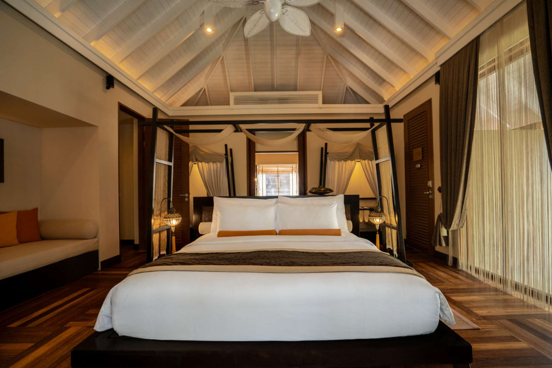 A second bedroom in a family beach villa at Ayada Maldives, white linen under a peaked roof