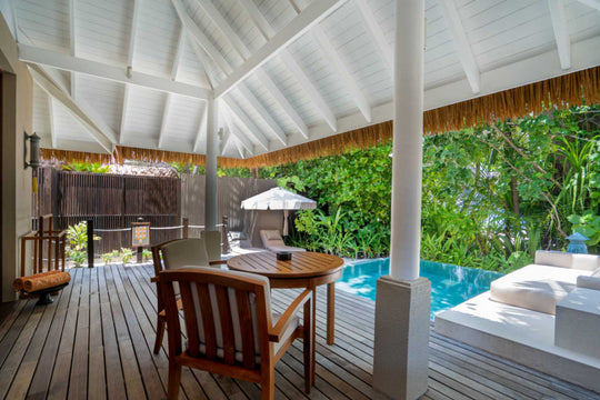 The deck of a family beach villa at Ayada Maldives, dining table and umbrella beside the pool