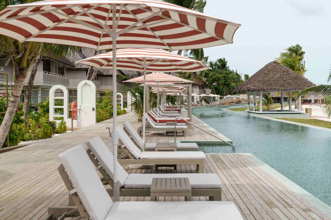 Sun Siyam Olhuveli, South Malé Atoll — pool deck with striped parasols and sun loungers beside the long pool