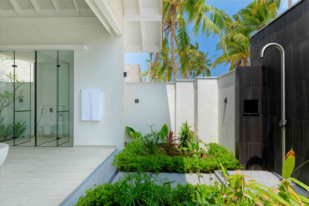 A walk-in shower and planted outdoor shower in a Beach Villa bathroom at ananea Madivaru Maldives