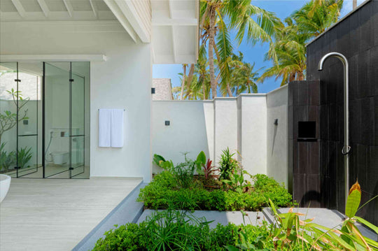 A walk-in shower and planted outdoor shower in a Beach Villa bathroom at ananea Madivaru Maldives