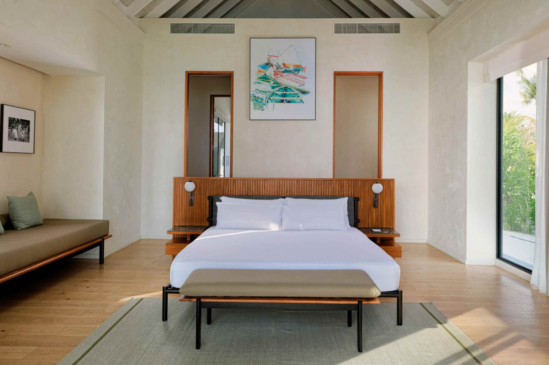 A Beach Villa bedroom at ananea Madivaru Maldives, bed against a panelled headboard with a daybed alongside