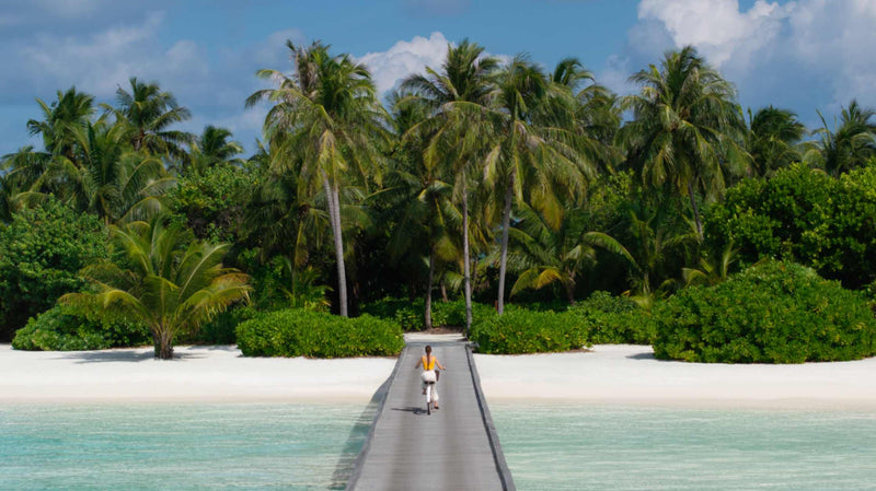 Guests cycling along the jetty past the overwater villas at Niyama Private Islands
