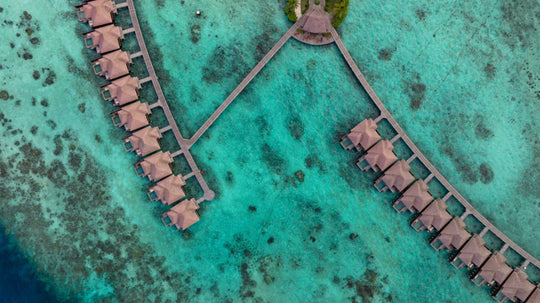 The two arms of overwater villas at Ayada Maldives, joined by timber walkways over the shallow reef