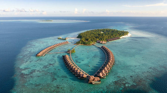 Aerial view of Ayada Maldives showing the island, its beach and the full loop of overwater villas