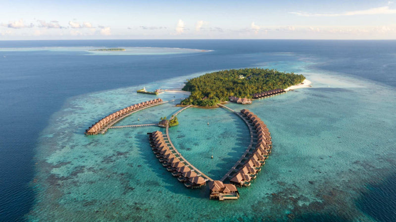 Aerial view of Ayada Maldives showing the island, its beach and the full loop of overwater villas