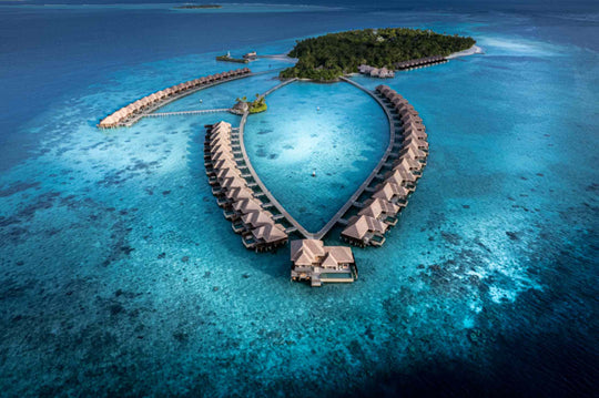 Ayada Maldives from the air at altitude, the reef dropping away into deep blue water