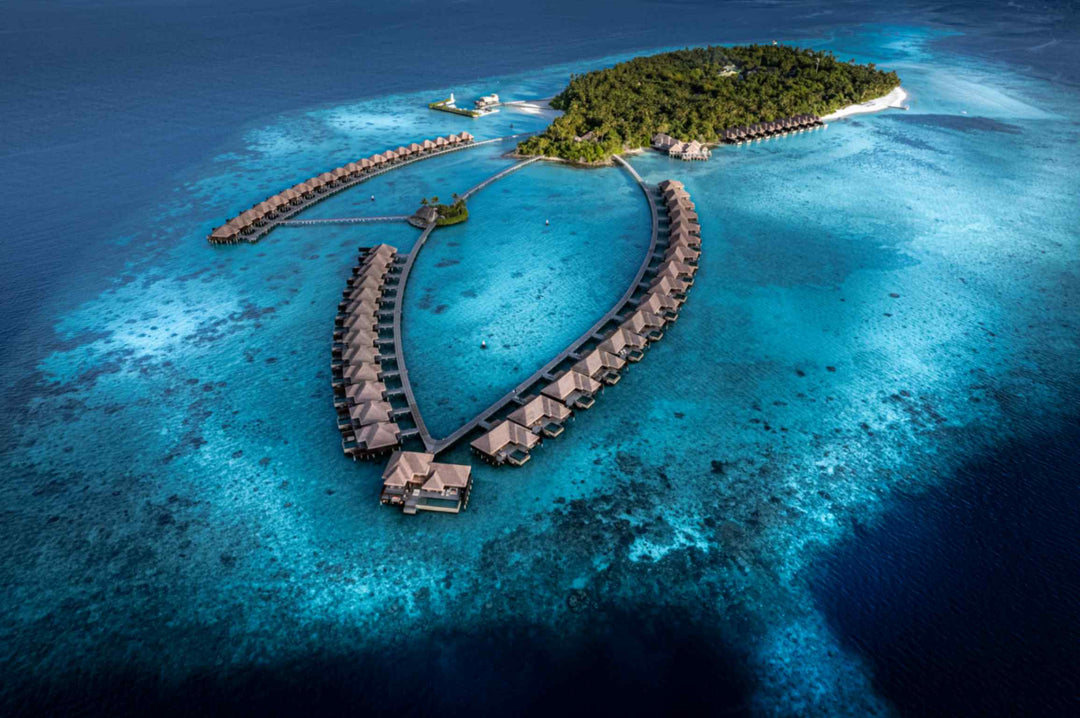 The overwater villa loop at Ayada Maldives seen from above with the island behind it
